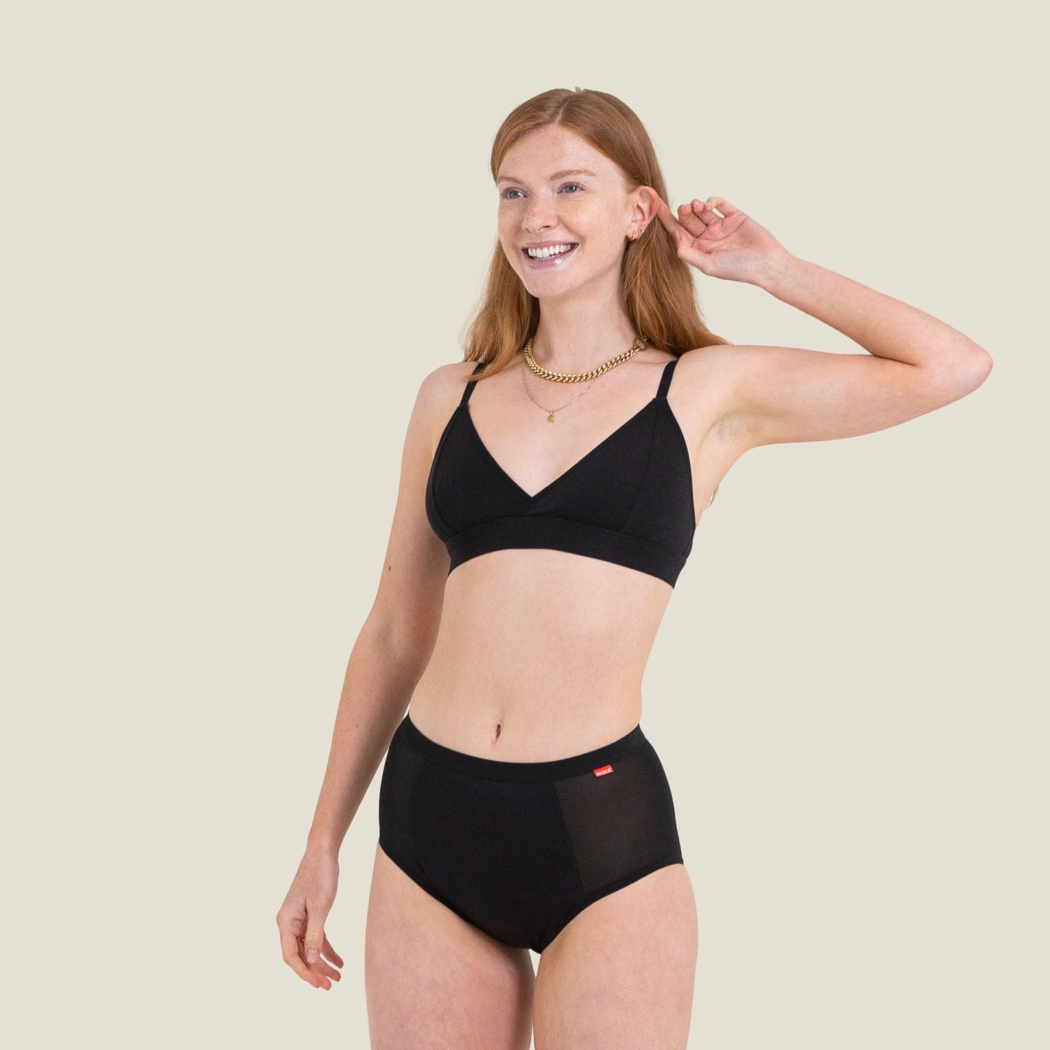 WUKA Ultimate™ High Waist period pants for super heavy flow, worn by a smiling model in a full-length studio shot.