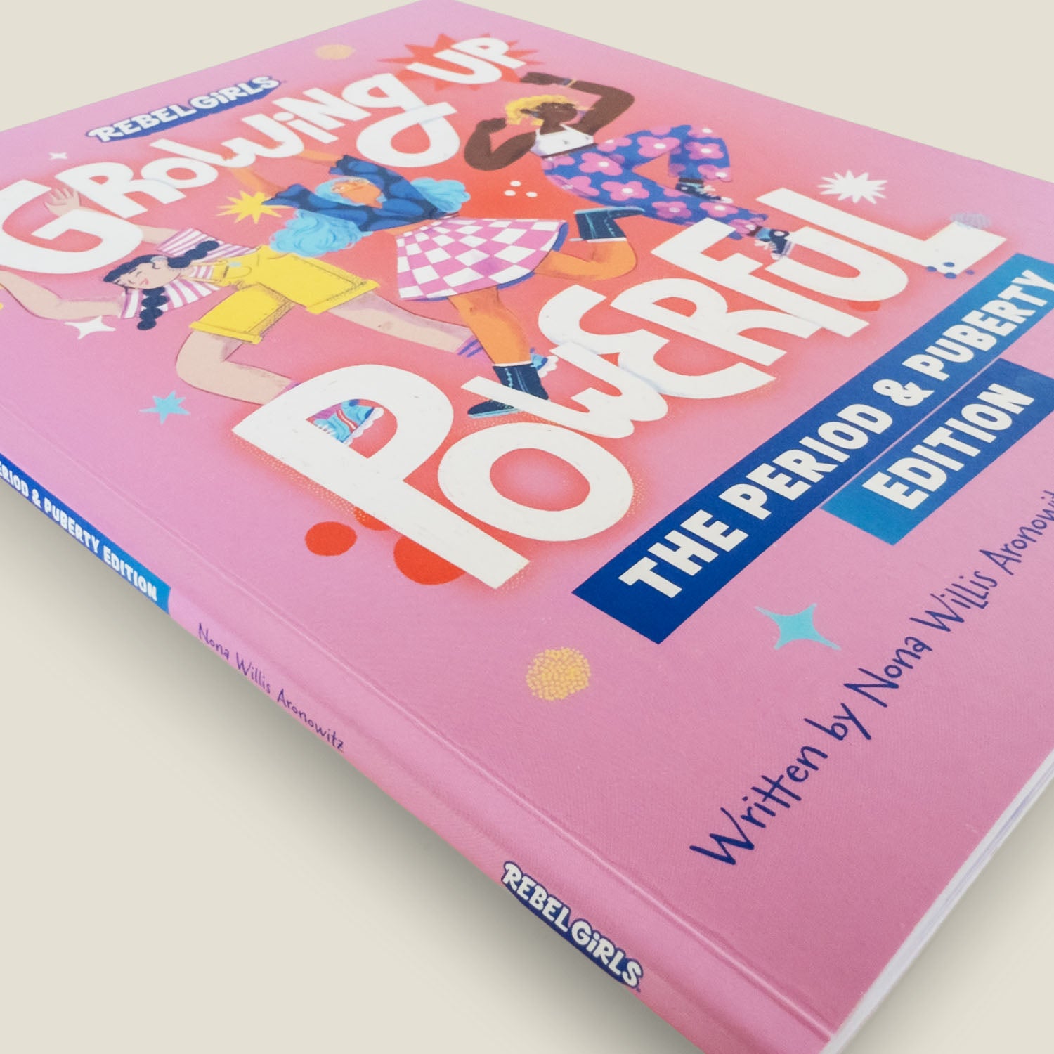 Close-up angled view of the "Growing Up Powerful" book cover, showing detailed illustrations and bold typography in bright pink tones.