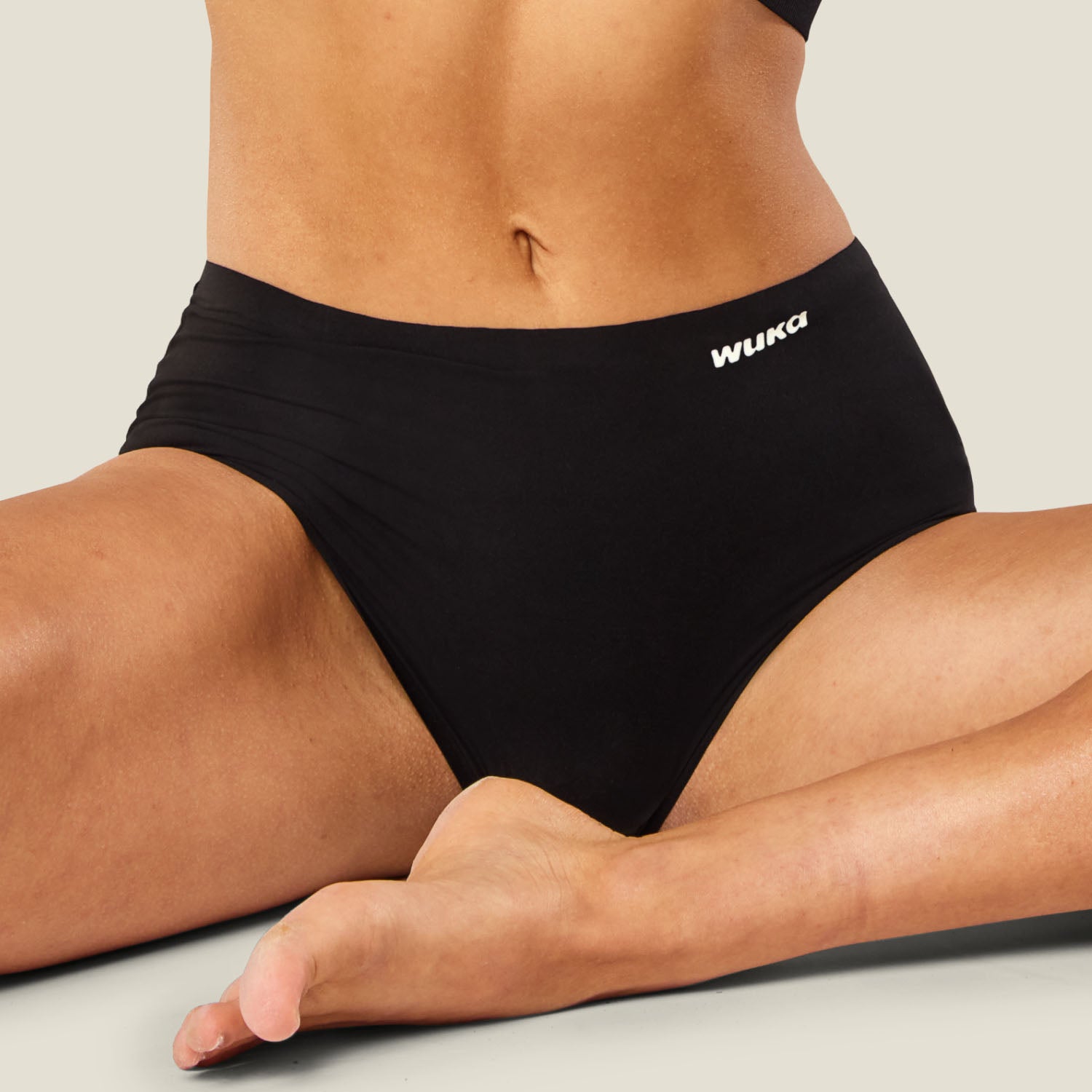 Lifestyle shot of model in seated position wearing WUKA Stretch™ Super Heavy Period Pants, ideal for overnight wear and maximum comfort.