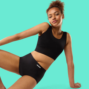 Teen wearing black WUKA Teen Stretch™ period underwear and crop top, smiling confidently against a teal background. Promoting 3 for £36 offer on reusable, leak-proof teen period pants designed to grow with you.
