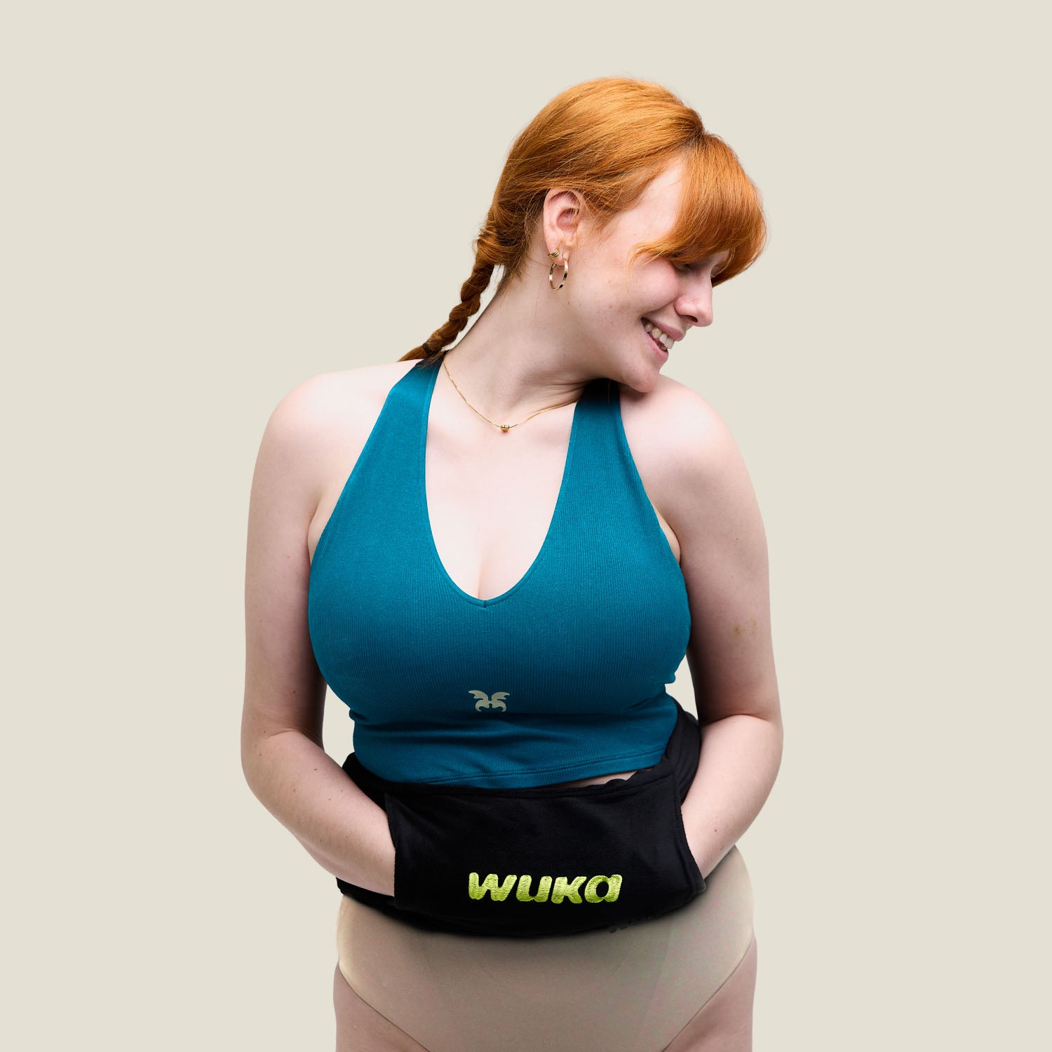 Model wearing WUKA period underwear and teal crop top with new branded WUKA hot water bottle held at the front